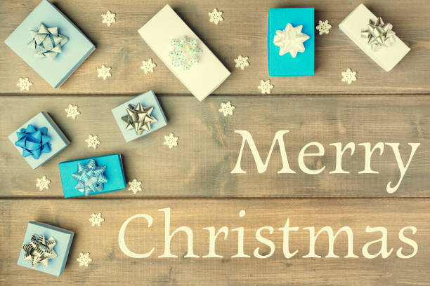 istock Christmas composition with the inscription Merry Christmas. White and blue gift boxes decorated with bows. Festive layout on a wooden background from boards. 1071034586