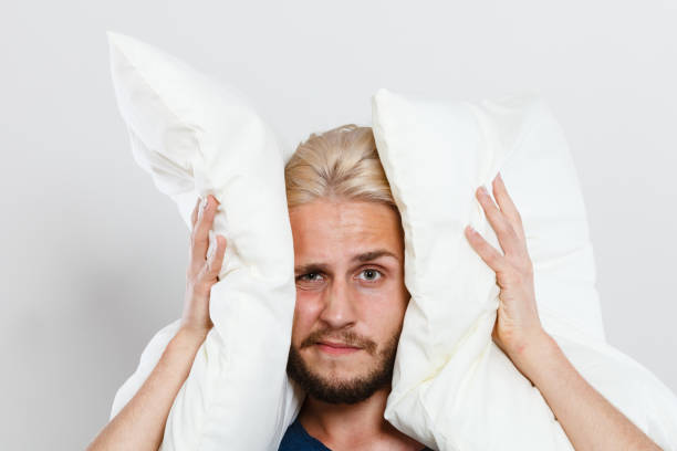 istock Sad man closing ears with pillows 1071039132