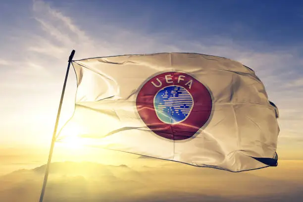 Union of European Football Associations UEFA flag on flagpole textile cloth fabric waving on the top sunrise mist fog