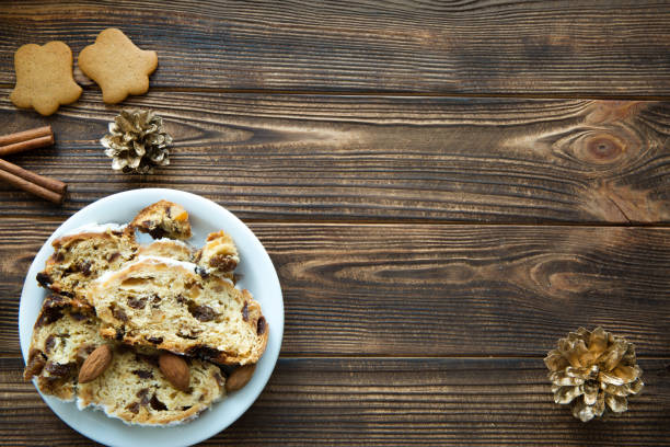 Christmas cake and gingerbread cookies on brown wooden table. Golden cones and cinnamon sticks decorations. Free space for text. Space for greeting and recipe.