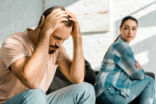 istock upset man with hands on head sitting on couch after arguing with wife on background 1071051932