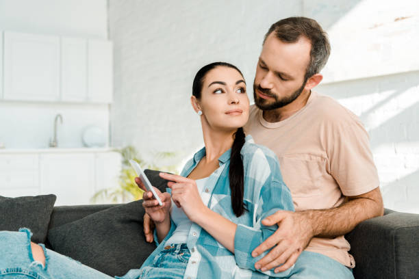 istock attractive couple sitting on couch and using smartphone at home 1071052160