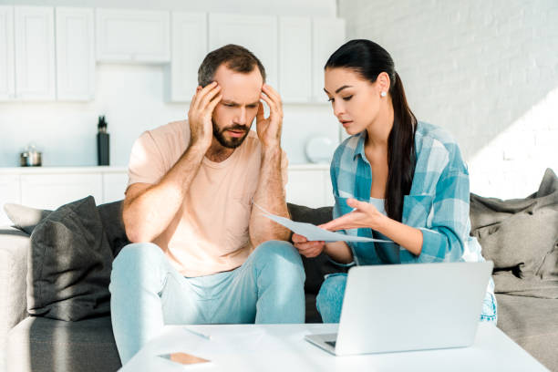 istock stressed couple sitting on couch, using laptop and having financial problems 1071052212