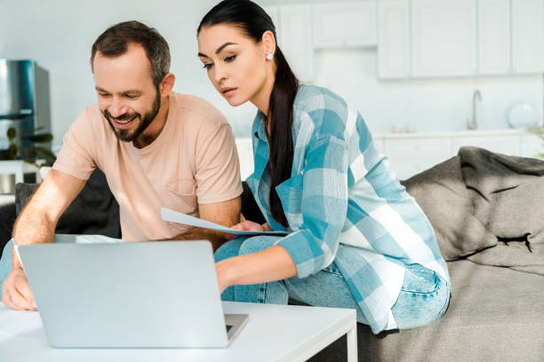 istock beautiful couple doing paperwork and using laptop at home 1071052214