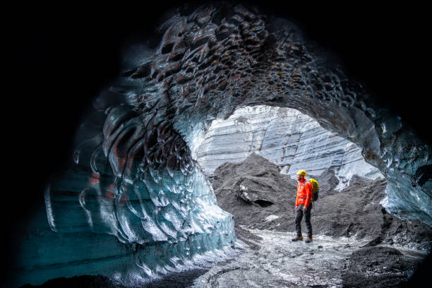 istock Hiker standing by ice cave at glacier in Iceland 1071053238