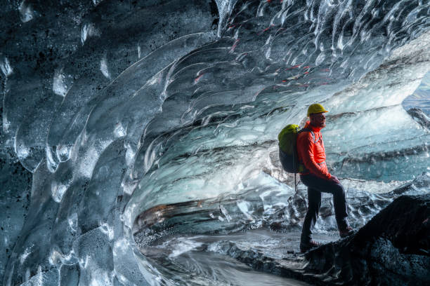 istock Man standing in ice cave in glacier 1071053440