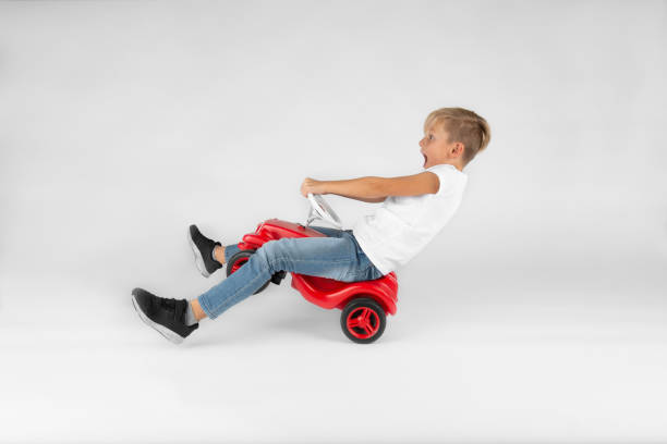 little blond boy is riding a toy vehicle little blond boy is riding a toy vehicle very fast and is screaming kid toy car stock pictures, royalty-free photos & images