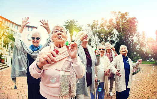 Shot of a group of senior women blowing bubbles together outdoors