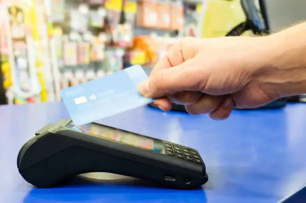 Photo of Mobile payments concept. Customer is paying using wireless or contact-less credit card and payment terminal with NFC technology