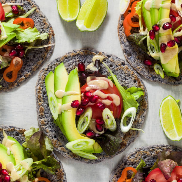 Gluten-free vegan tacos from black bean  with tomato and avocado salad  with tahini sauce and pomegranate seeds. healthy fast food for the whole family or party