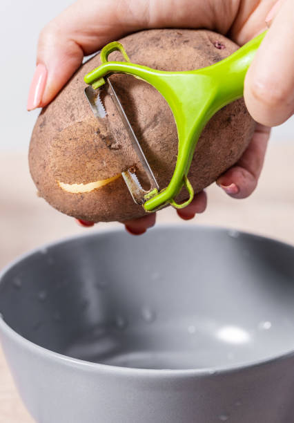 cuisinier de femme nettoie les pommes de terre - raw potato organic human skin food photos et images de collection