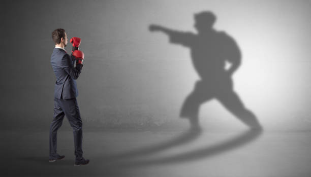 istock Young businessman fighting with his shadow 1071069142