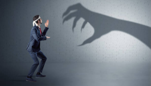 istock Businessman fighting with scary hand shadow 1071069328