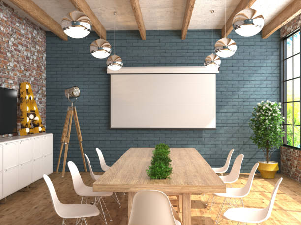 A meeting room with an empty white screen for the projector on the wall.