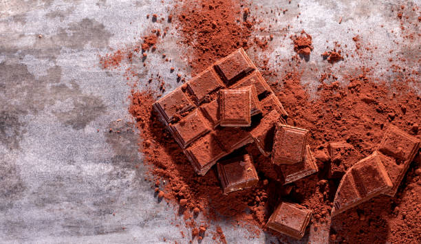 istock Broken chocolate pieces and cocoa powder on wooden 1071075644