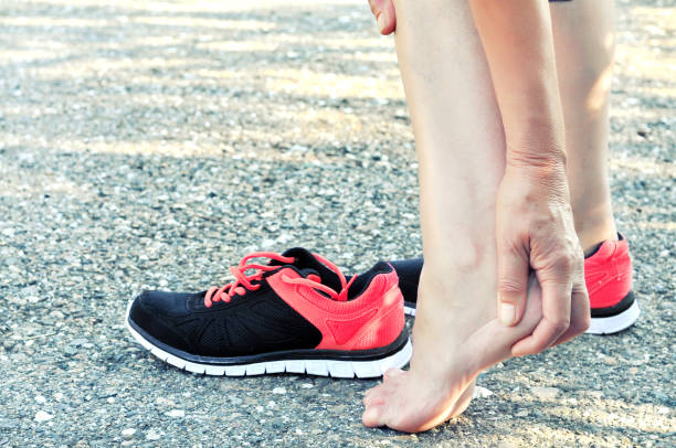 pain in the foot.running injury leg accident- sport woman runner hurting massaging painful sprained ankle in pain.athlete woman has heel injury, sprained ankle during running training. - twisted ankle fotos imagens e fotografias de stock