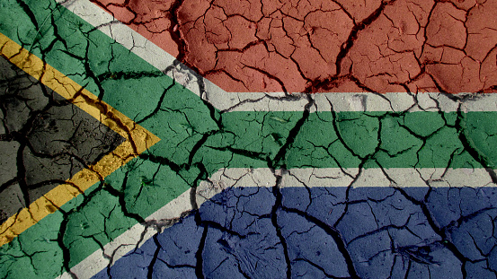 Political Crisis Or Environmental Concept: Mud Cracks With South Africa Flag