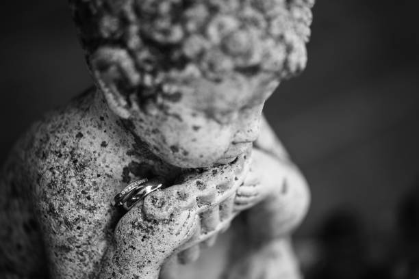 istock Two wedding rings on a stone statue of a boy 1071087904