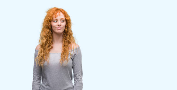 istock Young redhead woman smiling looking side and staring away thinking. 1071093322