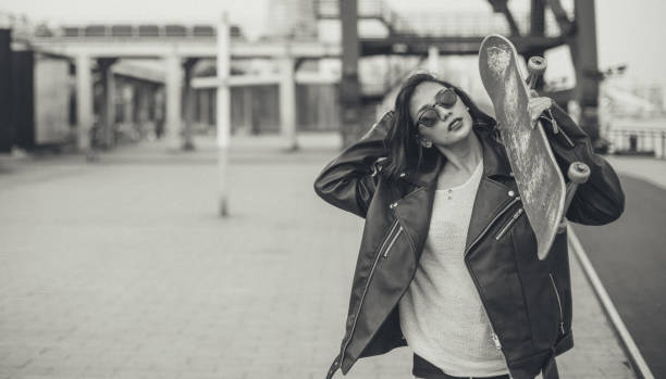 Woman holding skateboard on the shoulder outdoors