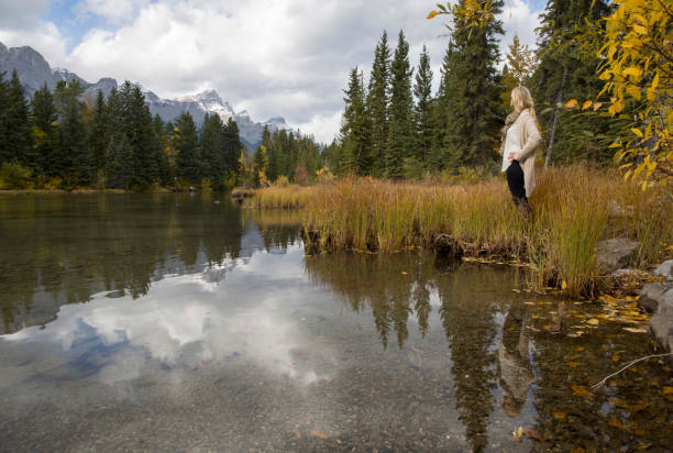 istock Woman stands beside mountain lake 1071099146