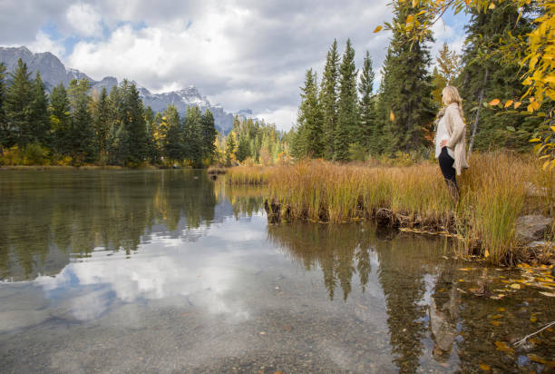 istock Woman stands beside mountain lake 1071099158