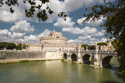 Rome, Italy - September 25, 2013: Daytime view of Castel Sant'Angelo on splendid day with nice cumulus clouds in autumn. Visitors on bridge over Tiber River.