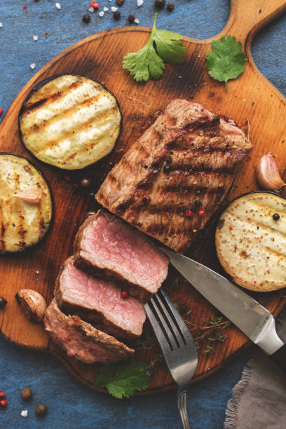 istock Grilled beef steak medium rare is sliced on a cutting board with spices and baked eggplants. Top view, flat lay. Toned 1071109556