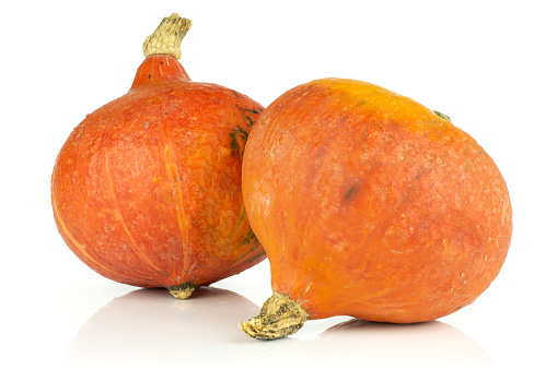 Group of two whole teardrop shaped fresh red kuri pumpkin hokkaido variety isolated on white background