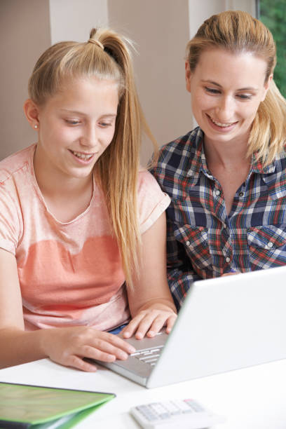 istock Female Home Tutor Helping Girl With Studies Using Laptop 1071114970