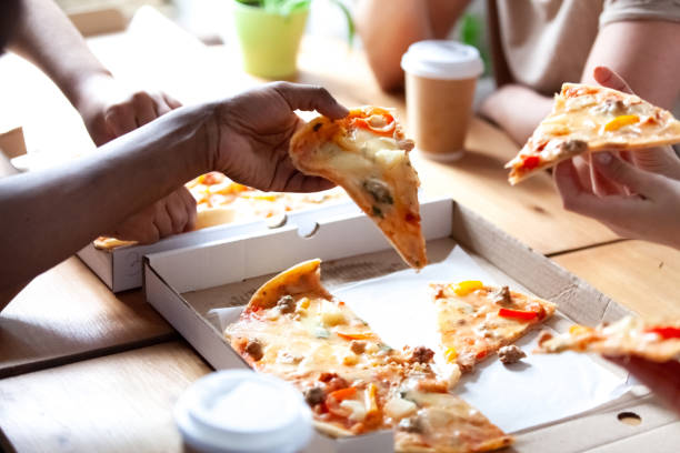 close up people hands holds pieces of pizza - pizza eating african descent lunch imagens e fotografias de stock