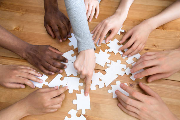 istock Close up hands of diverse people assembling puzzle 1071117696