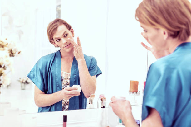 istock Short-haired good-looking transgender applying night cream with his hands 1071126102