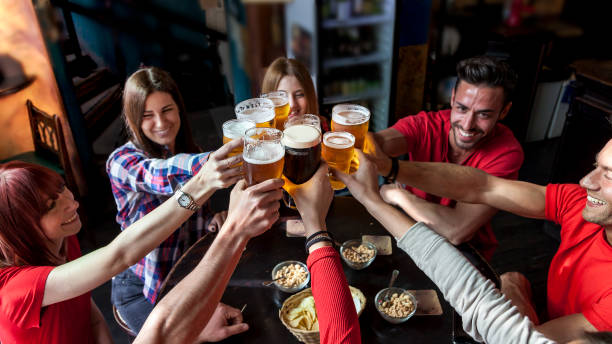 group of people celebrating in a pub - irish culture beer drinking pub imagens e fotografias de stock