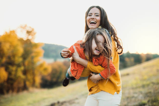 un ritratto di giovane madre con una piccola figlia nella natura autunnale al tramonto. - autumn women leaf scarf foto e immagini stock