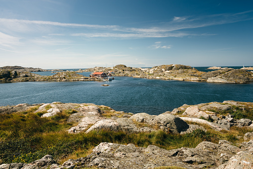 Sea landscape of a rocky coastline and a small town on the South of Sweden. Southern coastline of Sweden with view at rocky islands. White yacht in the sea.