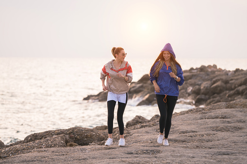 Two happy women exercise by the sea