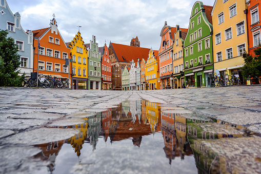 Traditional colorful gothic houses in the Old Town of Landshut, historical town in Bavaria by Munich, Germany, reflecting in a rain puddle