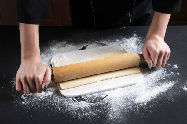 istock Woman preparing buns from puff pastryat table in bakery. The cook preparing buns at table in bakery. Cooking Process Of Apple Roses. Step four prepare the dough for baking. Cooking Process Concept 1071177892