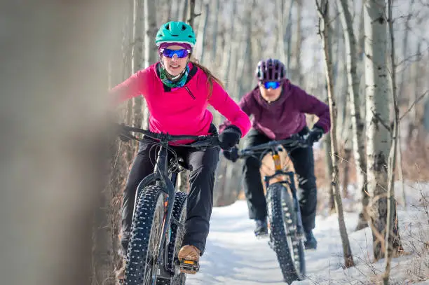 two female athletes riding fat bikes in the snow