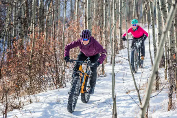 two female athletes riding fat bikes in the snow