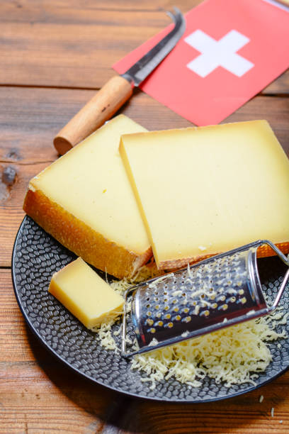 assortment of swiss cheeses emmental or emmentaler medium-hard cheese with round holes, gruyere, appenzeller and raclette used for traditional cheese fondue and gratin and flag of switzerland - cheese emmental cheese switzerland grated imagens e fotografias de stock