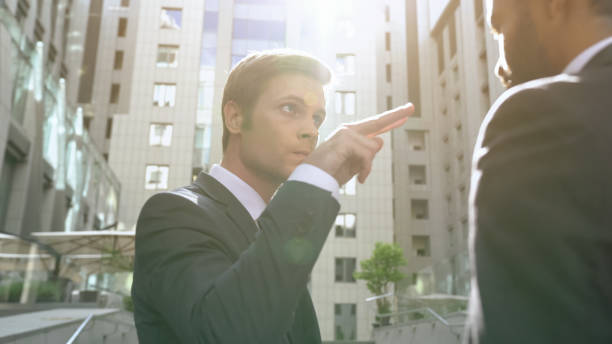 Young aggressive businessman making watching you gesture to employee, boss Young aggressive businessman making watching you gesture to employee, boss revenge stock pictures, royalty-free photos & images