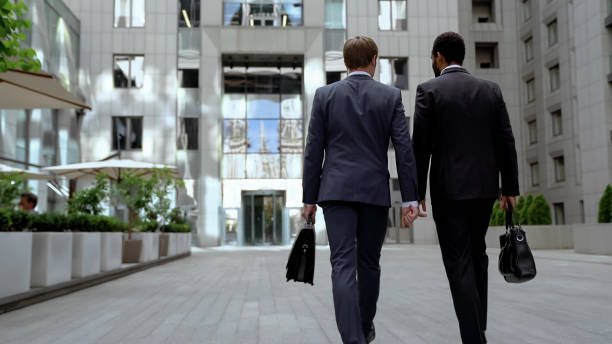 istock Two multiracial businessmen going to office building, discussing mutual work 1071225632