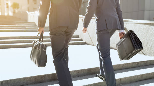 istock Businessmen approaching office building, climbing stairs, optimistic outlook 1071225742