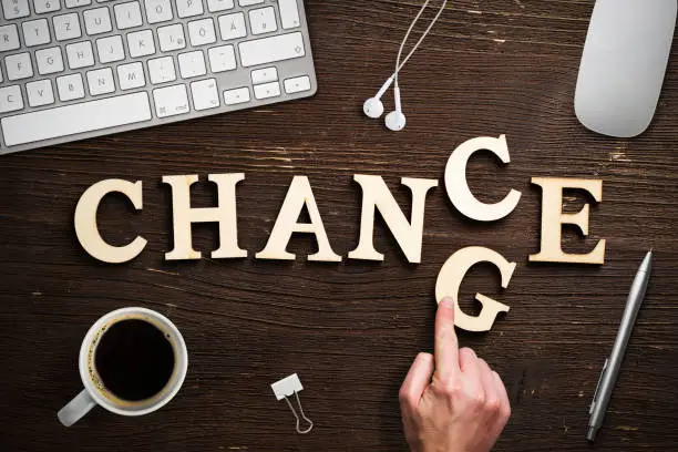 hand moving a letter, turning the word "change" to "chance" on dark wooden background