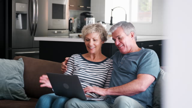 Senior couple on the couch at home using a laptop computer