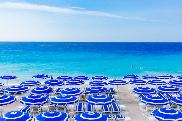 Blue umbrellas and chairs on beach by blue sea, in Nice, France stock photo