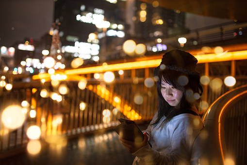 Woman using digital tablet in illuminated night city