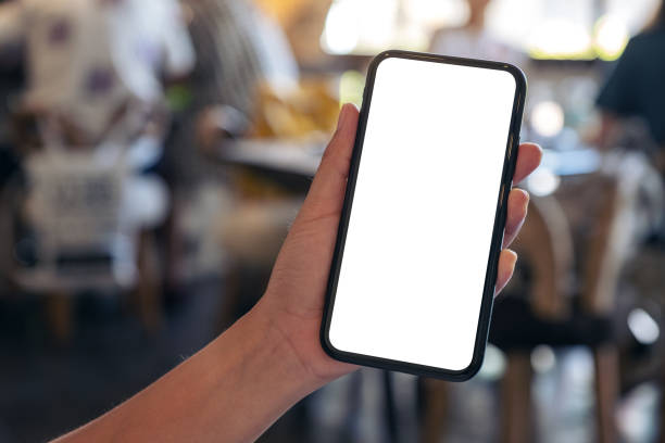 istock Mockup image of a hand holding black mobile phone with blank desktop screen with blur background in cafe 1071259876